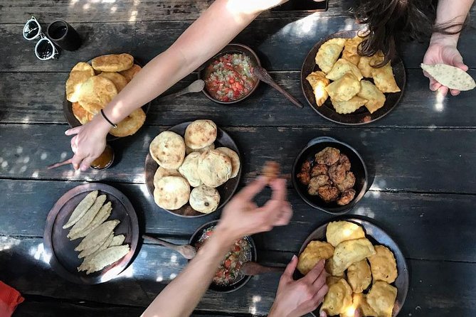 Mesa de madera con empanadas, sopaipillas y pebre para compartir