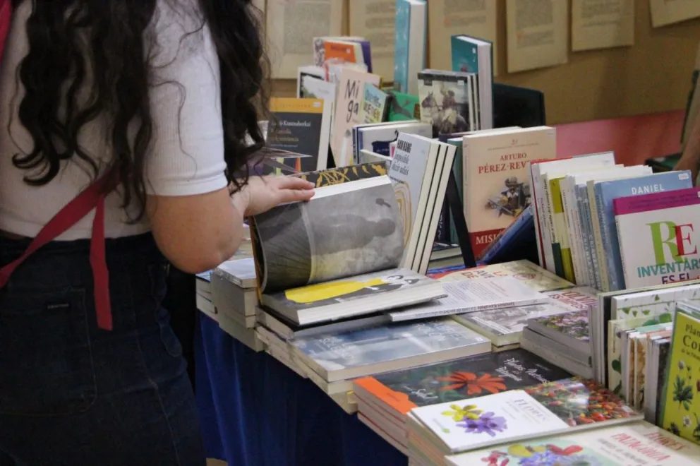 Una persona hojea libros en una mesa de la feria
