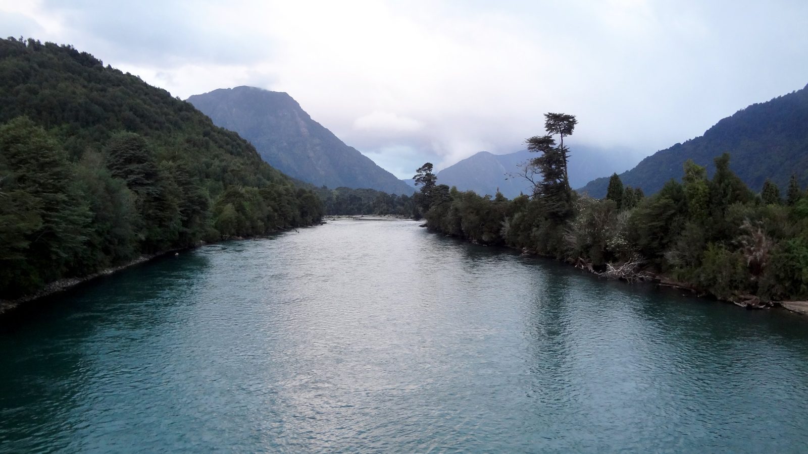 Turquoise river between forested hills