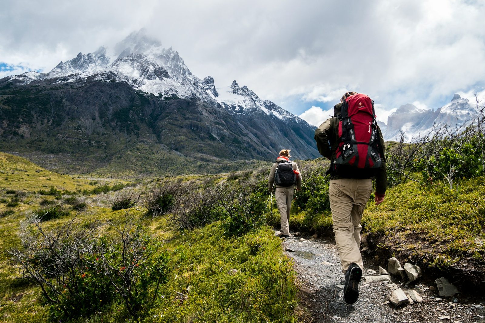 Two hikers walk toward snowy mountains in Patagonia